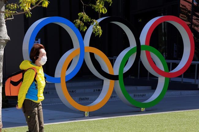 A woman walks past the Olympic rings in Tokyo, Wednesday, March 10, 2021. (AP Photo/Koji Sasahara)