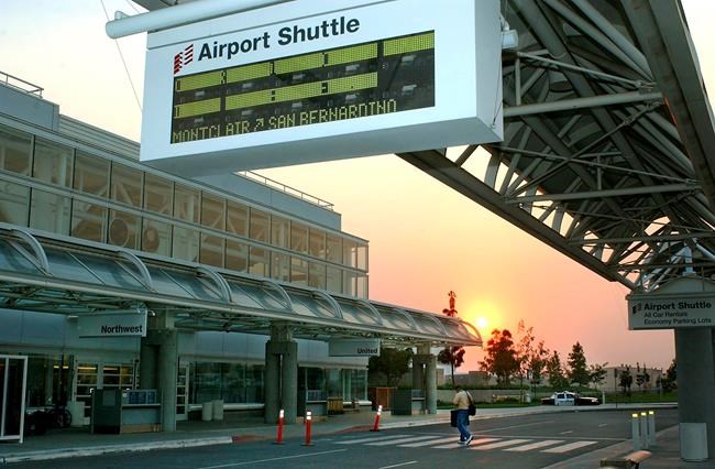 FILE - In this Oct. 26, 2003 file photo, a lone traveler walks through Ontario International Airport as the sun goes down in Ontario, Calif. A U.S. State Department official has told The Associated Press that a chartered plane sent to China to pick up Americans in the city of Wuhan has departed and is en route to the U.S. Wuhan is the epicenter of a new virus that has sickened thousands and killed more than 100. The official spoke on condition of anonymity because the official was not authorized to speak publicly. Its first stop is Anchorage, where travelers will be re-screened for the virus. Ontario International is the flight's ultimate destination. (AP Photo/Ric Francis, File)