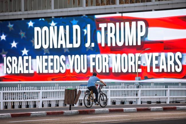 FILE - In this Oct. 21, 2020 file photo a cyclist rides next to a billboard supporting President Donald Trump, ahed of the U.S presidential election, in Tel Aviv, Israel. Tuesday's U.S. election, what's at stake if Donald Trump's presidency ends — or if it continues? Nation by nation, how is Election Day in the United States being watched, considered, assessed? (AP Photo/Oded Balilty, File)