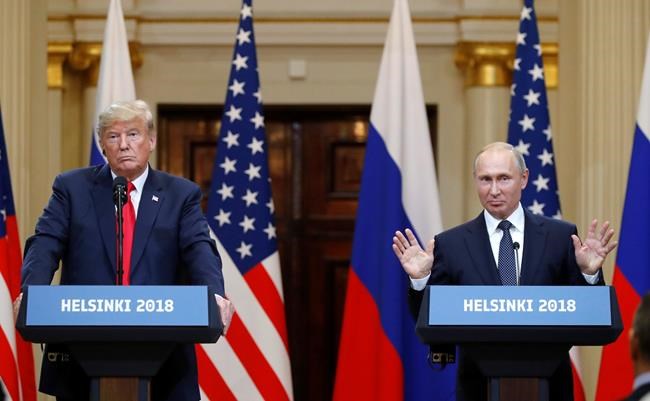 FILE - In this file photo taken on Monday, July 16, 2018, Russian President Vladimir Putin raises his hands as U.S. President Donald Trump, left, listens during a press conference after their meeting at the Presidential Palace in Helsinki, Finland. From Moscow, the U.S. election looks like a contest between