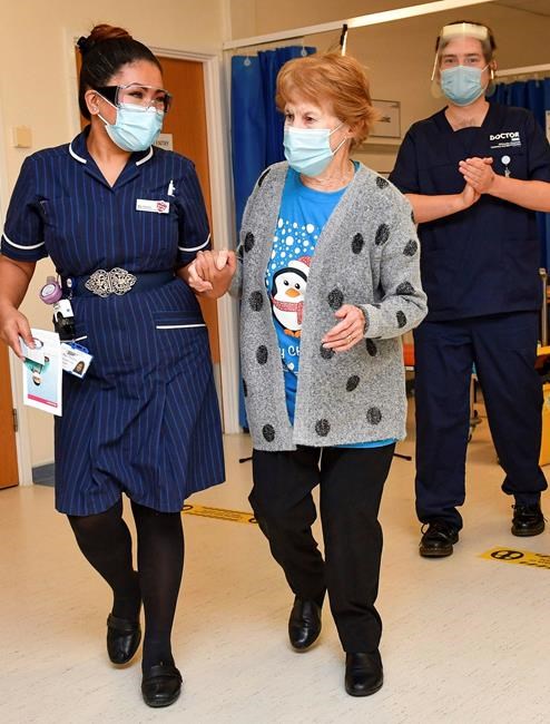 Margaret Keenan, 90, walks with nurse May Parsons after becoming the first person in the UK to receive the Pfizer-BioNTech COVID-19 vaccine, at University Hospital, Coventry, England, Tuesday Dec. 8, 2020. The United Kingdom, one of the countries hardest hit by the coronavirus, is beginning its vaccination campaign, a key step toward eventually ending the pandemic. (Jacob King/Pool via AP)