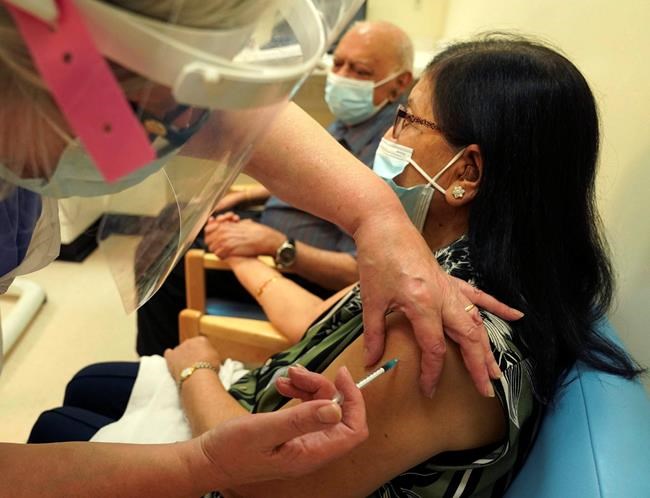 Ranju Shukla, accompanied by her husband Dr Hari Shukla, receives the Pfizer-BioNTech COVID-19 vaccine at the Royal Victoria Infirmary in Newcastle, England, Tuesday Dec. 8, 2020. The United Kingdom, one of the countries hardest hit by the coronavirus, is beginning its vaccination campaign, a key step toward eventually ending the pandemic. (Owen Humphreys/Pool via AP)