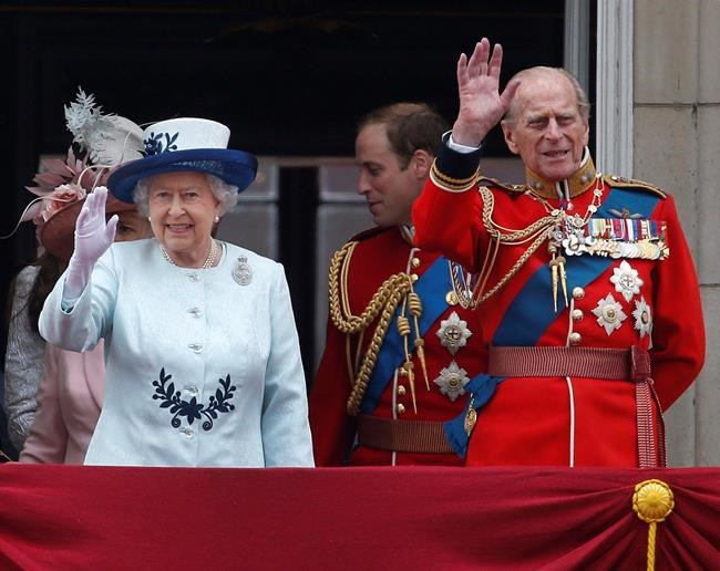 FILE - In this Saturday, June 14, 2014 file photo, Britain's Queen Elizabeth II, accompanied by Prince Philip, wave to the crowds from the balcony of Buckingham Palace, during the Trooping The Colour parade, in central London. Prince Philip was the longest serving royal consort in British history. In Britain, the husband or wife of the monarch is known as consort, a position that carries immense prestige but has no constitutional role. (AP Photo/Lefteris Pitarakis, File)