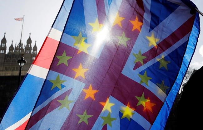 An anti-Brexit campaigner waves European Union and Union flags outside Parliament in London, Wednesday, Jan. 29, 2020. Britain officially leaves the European Union on Friday after a debilitating political period that has bitterly divided the nation since the 2016 Brexit referendum. (AP Photo/Kirsty Wigglesworth)