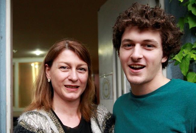 FILE - In this Thursday April 28, 2016 file photo, former champion Nino Salukvadze, left, and her son Tsotne Machavariani pose for a photo during an interview with the Associated Press in Tbilisi, Georgia. Even if it takes an extra year, Salukvadze will still be aiming for an Olympic record. The Georgian shooter has competed at every Olympics since 1988, where she won a gold medal for the Soviet Union. At the Tokyo Olympics — now postponed until 2021 because of the coronavirus pandemic — she will set a women's record of nine appearances. (AP Photo/Shakh Aivazov, file)