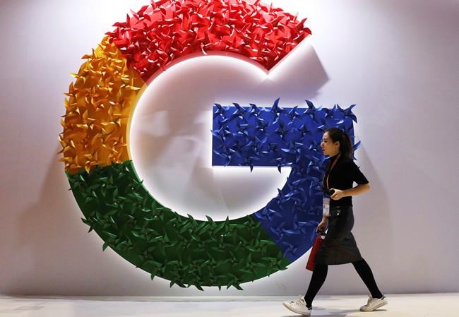 FILE - In this Monday, Nov. 5, 2018 file photo, a woman walks past the logo for Google at the China International Import Expo in Shanghai. By U.S. standards, the Justice Department's move to sue Google this week for abusing its dominance in online search and advertising was a bold move. But it treads on ground already broken years before by EU officials in Brussels. (AP Photo/Ng Han Guan, File)