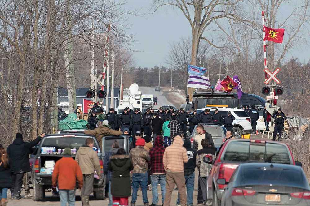 Protesters speak to Ontario Provincial Police officers at a rail blockade in Tyendinaga Mohawk Territory, near Belleville, Ont., on Monday Feb. 24, 2020, as they protest in solidarity with Wet