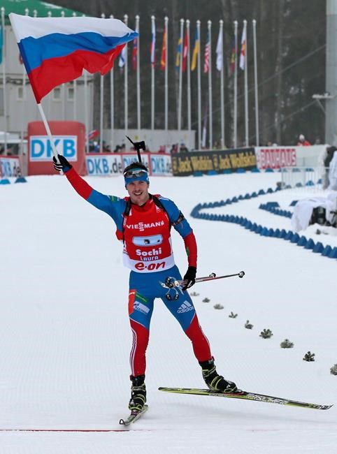 FILE - In this file photo dated Sunday, March 10, 2013, member of the winning Russian relay team Evgeny Ustyugov holds the Russian national flag aloft as he finishes in the men's 4X7.5 km Relay during the IBU World Cup Biathlon in Sochi, Russia. The International Biathlon Union on Saturday Feb. 15, 2020, issued a two-year ban for Russia's Evgeny Ustyugov, who was part of the gold medal-winning men’s relay team at the 2014 Sochi Winter Olympics. (AP Photo/Mikhail Metzel, FILE)