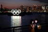 Two women take a selfie with the Olympic rings in the background in the Odaiba section of Tokyo, Thursday, March 12, 2020. Doping testers around the sporting world are trying to avoid infecting themselves or athletes during the global virus outbreak, and that's not easy when collecting samples means getting very close to sports stars. (AP Photo/Jae C. Hong)