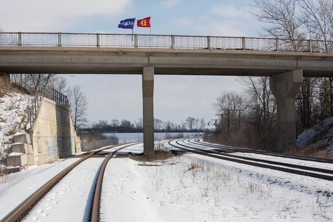 A Six Nations flag, left, and a Mohawk warrior flag fly on a bridge over the closed train tracks in Tyendinaga Mohawk Territory, Ont. on Wednesday, Feb. 12, 2020, in support of Wet'suwet'en's blockade of a natural gas pipeline in northern B.C. THE CANADIAN PRESS/Lars Hagberg