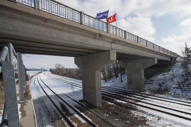 A Six Nations flag, left, and a Mohawk warrior flag fly on a bridge over the closed train tracks in Tyendinaga Mohawk Territory, Ont. on Wednesday, Feb. 12, 2020, in support of Wet'suwet'en's blockade of a natural gas pipeline in northern B.C. THE CANADIAN PRESS/Lars Hagberg