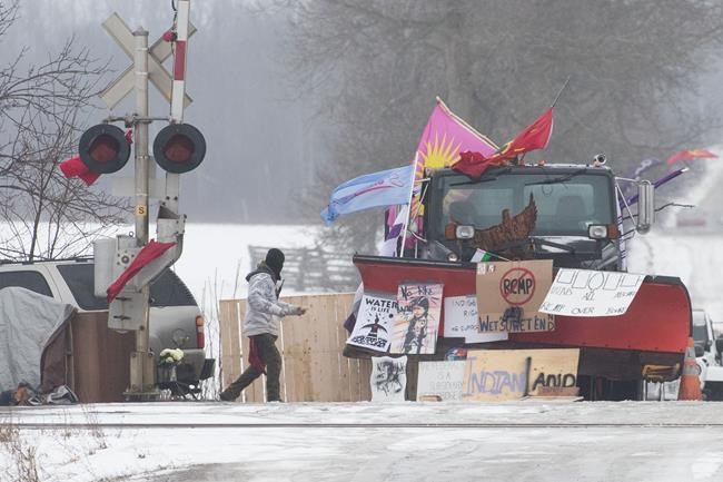 A Protester walk near closed train tracks in Tyendinaga Mohawk Territory near Belleville, Ont. on Tuesday, Feb. 18, 2020, as they protest in solidarity with the Wet'suwet'en hereditary chiefs opposed to the LNG pipeline in northern British Columbia. THE CANADIAN PRESS/Lars Hagberg