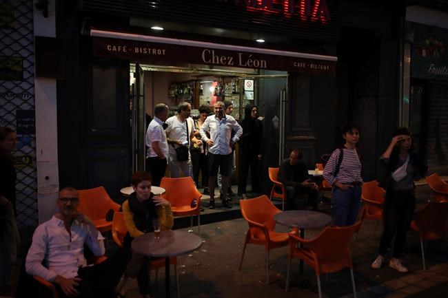Clients who enjoyed their first drinks in a cafe after he lockdown watch police advancing during a demonstration Tuesday, June 2, 2020 in Marseille, southern France. Thousands of people defied a police ban and converged on the main Paris courthouse for a demonstration to show solidarity with U.S. protesters and denounce the death of a black man in French police custody. (AP Photo/Daniel Cole)