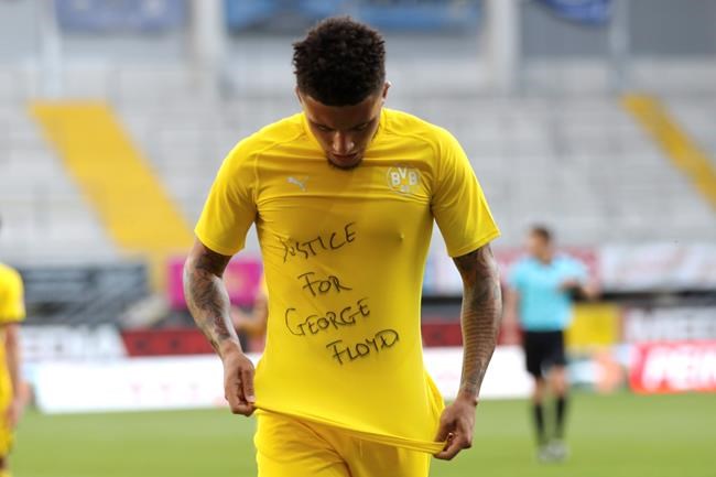Jadon Sancho of Borussia Dortmund celebrates scoring his teams second goal of the game with a 'Justice for George Floyd' shirt during the German Bundesliga soccer match between SC Paderborn 07 and Borussia Dortmund at Benteler Arena in Paderborn, Germany, Sunday, May 31, 2020. Because of the coronavirus outbreak all soccer matches of the German Bundesliga take place without spectators. (Lars Baron/Pool via AP)