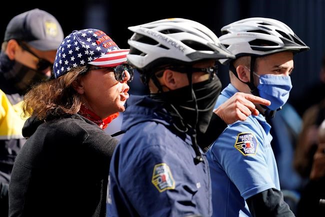A protester behind Philadelphia police officers argues her point outside the Pennsylvania Convention Center where votes are being counted, Thursday, Nov. 5, 2020, in Philadelphia, following Tuesday's election. (AP Photo/Matt Slocum)