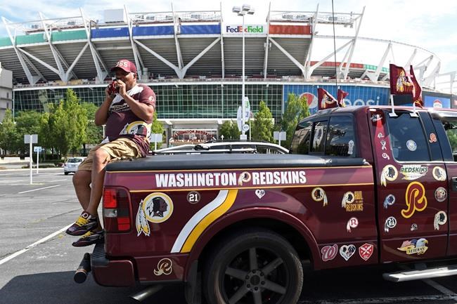 Rodney Johnson of Chesapeake, Va., sits on the back of his truck outside FedEx Field in Landover, Md., Monday, July 13, 2020. The Washington NFL franchise announced Monday that it will drop the