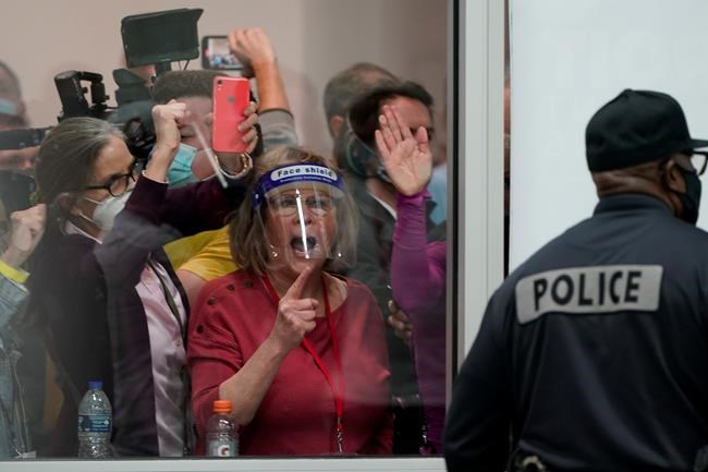 Election challengers yell as they look through the windows of the central counting board as police were helping to keep additional challengers from entering due to overcrowding, Wednesday, Nov. 4, 2020, in Detroit. (AP Photo/Carlos Osorio)