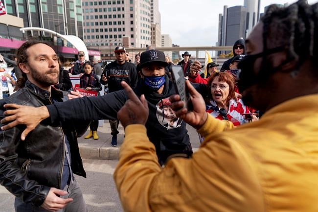 Trump supporter Charles Littleton, center, helps separate a fellow Trump supporter, left, from Biden supporter Angelo Austin, right, as they argue outside the central counting board at the TCF Center in Detroit, Thursday, Nov. 5, 2020. (AP Photo/David Goldman)