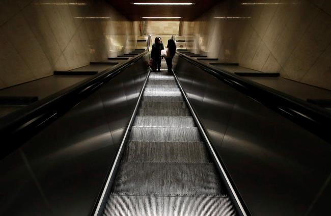 Two people stand in an empty staircase leading to the subway, in Milan, northern Italy, Wednesday, Feb. 26, 2020. Italy has been struggling to contain the rapidly spreading outbreak that has given the country more coronavirus cases outside Asia than anywhere else. (AP Photo/Antonio Calanni)
