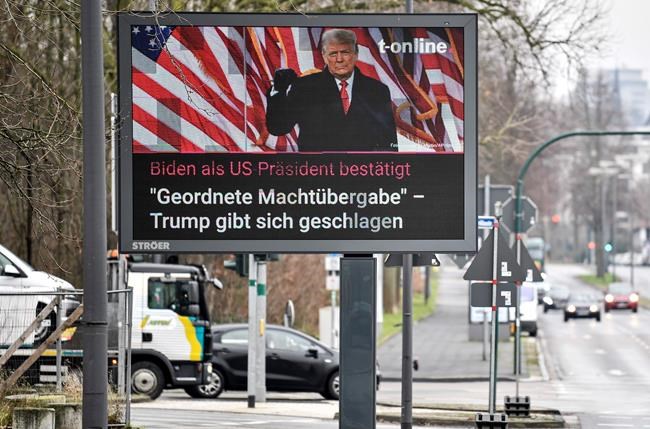 A large news screen beside a street in Essen, Germany, showing US president Donald Trump, and a headline reading 'Biden as US president confirmed, orderly transfer of power - Trump declares defeat' on Thursday, Jan. 7, 2021. (AP Photo/Martin Meissner)