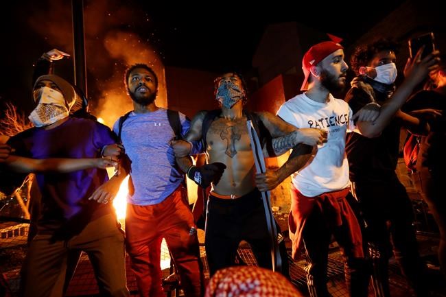 John Minchillo / The Associated Press
Protestors demonstrate outside of a burning Minneapolis 3rd Police Precinct, Thursday, May 28, 2020, in Minneapolis. Protests over the death of George Floyd, a black man who died in police custody Monday, broke out in Minneapolis for a third straight night. (AP Photo/John Minchillo)