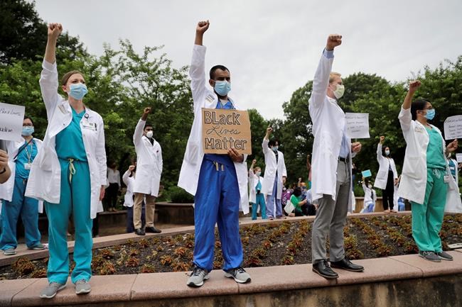Healthcare professionals gather outside Barnes-Jewish Hospital to demonstrate in support of the Black Lives Matter movement Friday, June 5, 2020, in St. Louis, Mo. The White Coats for Black Lives protest was organized to stand in solidarity with those speaking out against the death of George Floyd who died after being restrained by Minneapolis police officers on May 25. (AP Photo/Jeff Roberson)