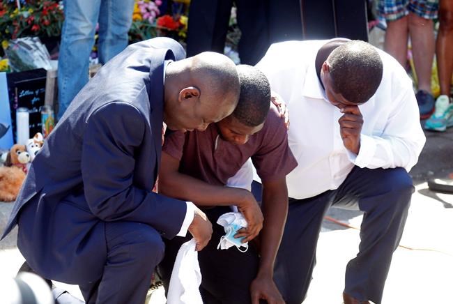 Quincy Mason, center, the son of George Floyd, and family attorney Ben Crump, left, kneel, Wednesday, June 3, 2020 as they visited the site of a memorial in Minneapolis where Floyd was arrested on May 25 and died while in police custody. Video shared online by a bystander showed a white officer kneeling on his neck during his arrest as he pleaded that he couldn't breathe. (AP Photo/Jim Mone)