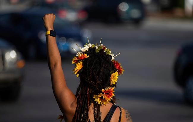 SeaSea Stark, of Omaha, raises her fist as protesters gather at 72nd and Dodge in Omaha on Monday, Aug. 24, 2020. The protest was organized in response to the shooting of Jacob Blake, a Black man in Wisconsin, who was shot multiple times in the back by police on Sunday. (Anna Reed/Omaha World-Herald via AP)