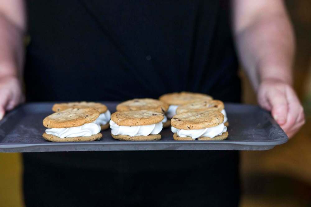 Pennyweight Market co-owner Laurie McLean holds up a tray of kid-sized chocolate chip and vanilla ice cream sandwiches. (Mikaela MacKenzie / Winnipeg Free Press)