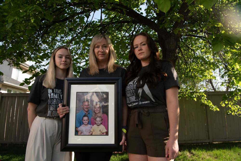 ALEX LUPUL / WINNIPEG FREE PRESS FILES Jo-Anne McNeil holds a family photo with her daughters Sarah and Taylor at their home in Winnipeg.