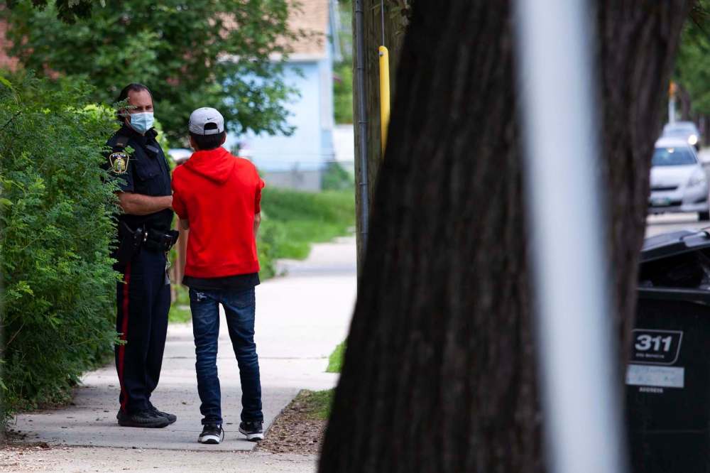 A police officer speaks to a youth regarding the stabbing. (Daniel Crump / Winnipeg Free Press)