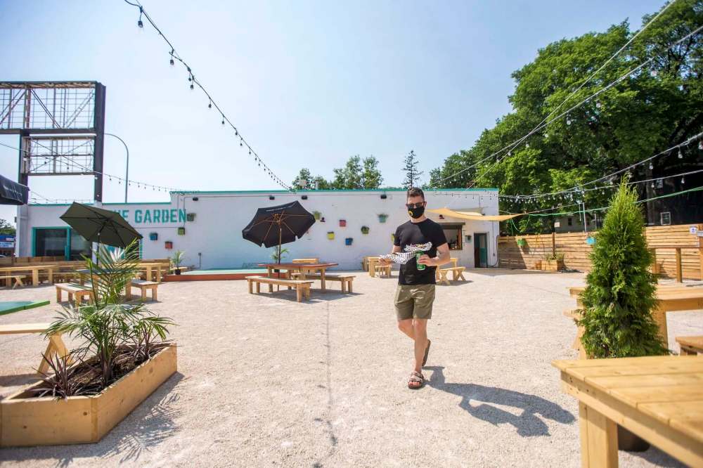 MIKAELA MACKENZIE / WINNIPEG FREE PRESS
Scott Angus walks drinks and food back to his table at The Garden 955, a new beer garden at 955 Portage Avenue.
