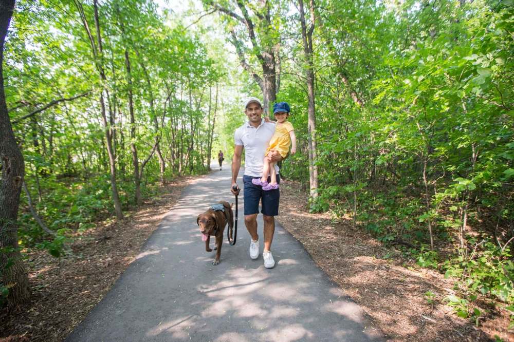 Gordon Templeton, daughter Naomi, and their dog, Nala, who is sporting the Optimus Gear Co. defender harness. (Mikaela MacKenzie / Winnipeg Free Press)