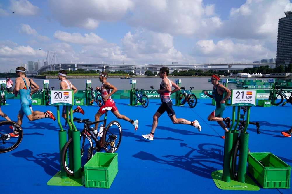 Tyler Mislawchuk (centre) runs through the second transition during the men’s individual triathlon at the Summer Olympics in Tokyo. (David Goldman / The Associated Press)