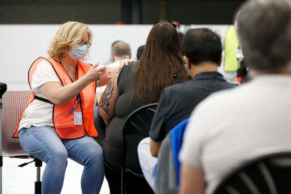 The fourth wave will be minimized if Manitobans, such as those awaiting their shot from Karen Balzer, continue to get vaccinated. (John Woods / The Canadian Press)