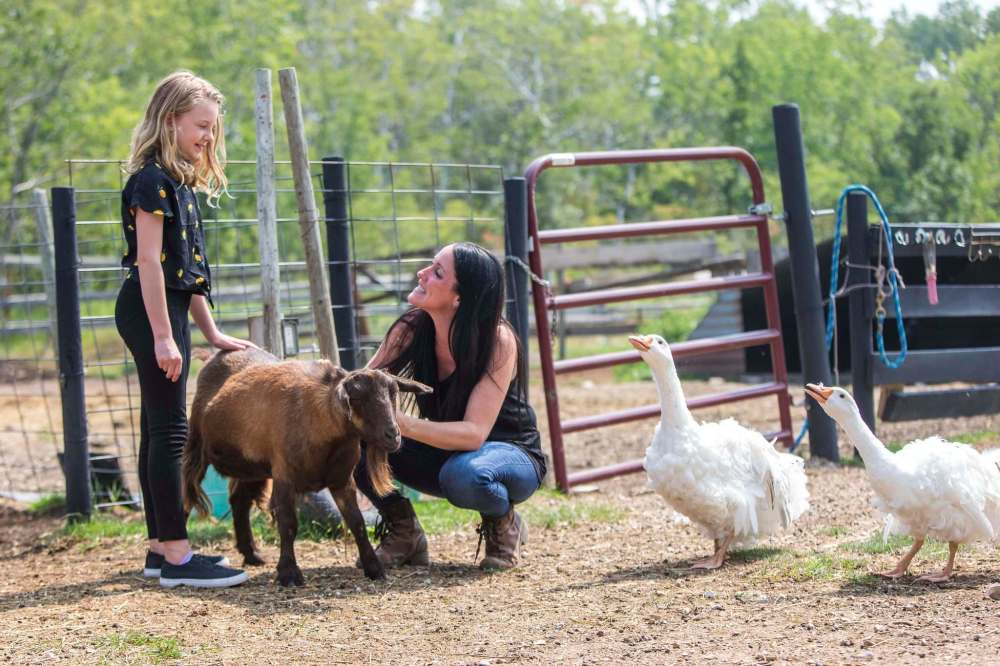 Macyn Comeault (left) and Lucy Sloan hang out with the animals at Lil’ Steps Wellness Farm in St. Malo. Sloan has been practicing animal-assisted therapy on her farm since 2015. (Mikaela MacKenzie / Winnipeg Free Press)