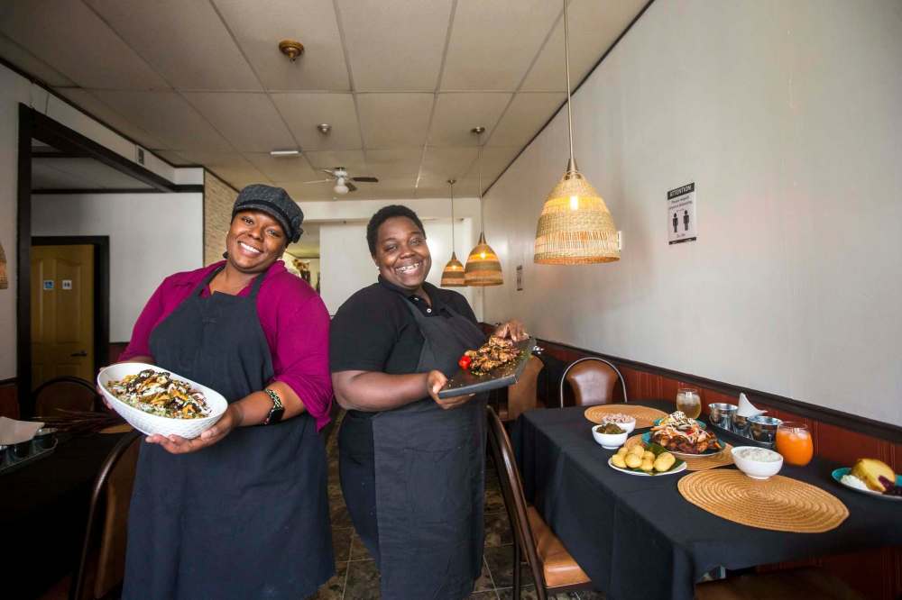 Coleman and Gilman show off two of their signature dishes, the oxtail bowl and jerk wings. (Mikaela MacKenzie / Winnipeg Free Press)
