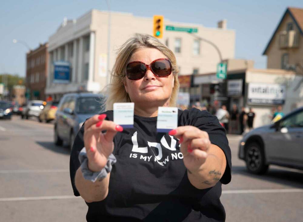 JESSICA LEE/WINNIPEG FREE PRESS
Allie Friedenberg holds up a ripped vaccine card Wednesday at the protest outside the Health Sciences Centre against vaccines, vaccine passports and COVID restrictions.