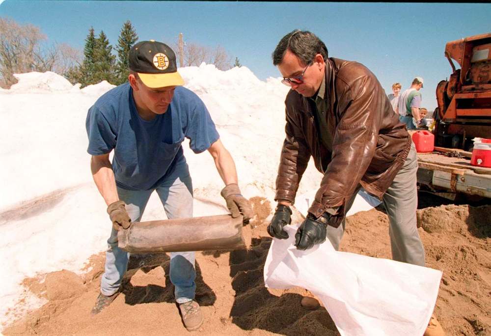 Gary Filmon (right) helps build a sandbag dike at an Emerson-area farm in 1997. Filmon calls the Flood of the Century the greatest challenge he faced as Manitoba’s premier. (Jeff De Booy / Winnipeg Free Press files)