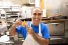 Gerry Lomonaco, owner of Sorrento Pizza on Ellice Avenue, holds up a picture of himself working in the same kitchen he still works in 36 years later.