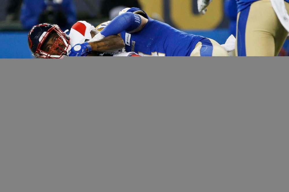 Winnipeg Blue Bombers linebacker Adam Bighill (top) tackles Montreal Alouettes’ Cameron Artis-Payne Saturday night at IG Field. The Blue won their 11th game of the season and their ninth in a row. (John Woods / The Canadian Press files)
