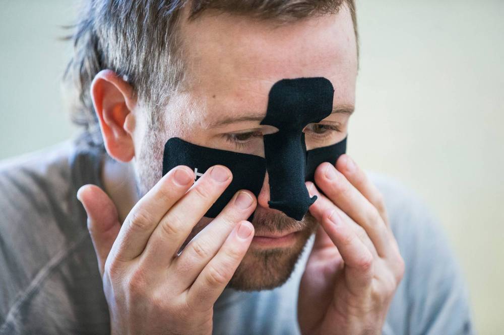 MIKAELA MACKENZIE / WINNIPEG FREE PRESS
Perry puts kinesiology tape on his face to prevent frostbite.