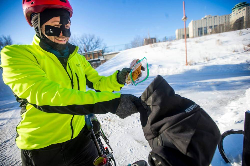 MIKAELA MACKENZIE / WINNIPEG FREE PRESS
Perry dumps snacks into his pogies (insulated handlebar mitts) to sustain him on long winter rides.