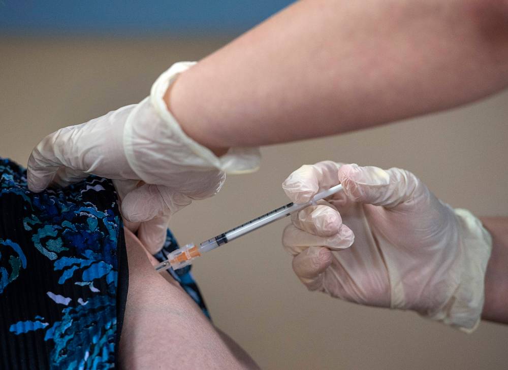 Amanda Parsons, a registered nurse on staff at the Northwood Care facility, administers a dose of the Moderna vaccine to Ann Hicks in Halifax on Monday, Jan. 11, 2021. In a bid to control COVID-19, the federal government plans to make free vaccines available to everyone who lives in Canada over the course of 2021. THE CANADIAN PRESS/Andrew Vaughan-Pool