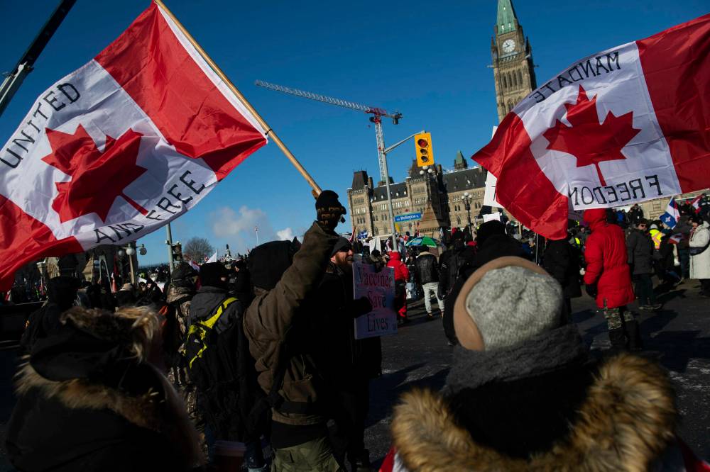 People wave flags during a rally against COVID-19 restrictions on Parliament Hill, which began as a cross-country convoy protesting a federal vaccine mandate for truckers, in Ottawa, on Saturday, Jan. 29, 2022. (Justin Tang / The Canadian Press)