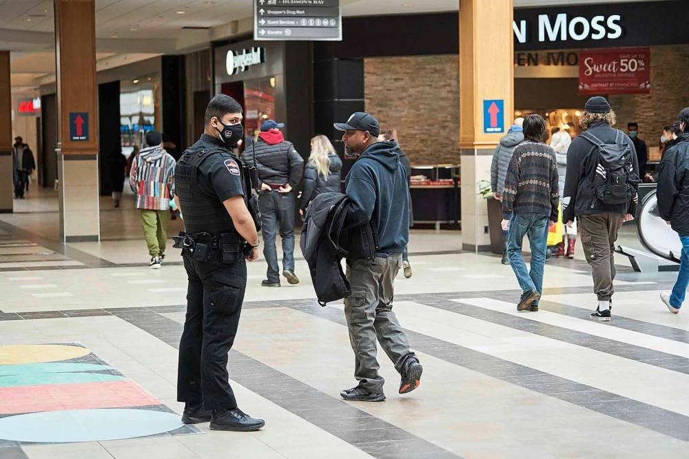 A security guard speaks with a protester who walked around CF Polo Park Mall without the required face mask. (David Lipnowski / Winnipeg Free Press)