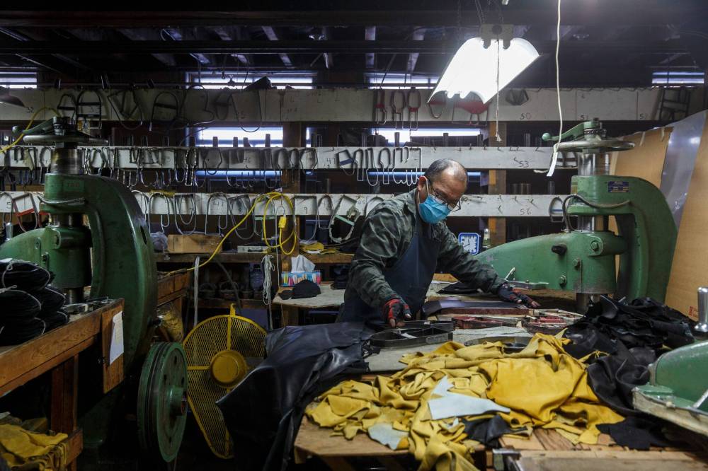 MIKE DEAL / WINNIPEG FREE PRESS
June Del Rosario cuts each piece of leather with a die for a pair of Garbage Mitts.