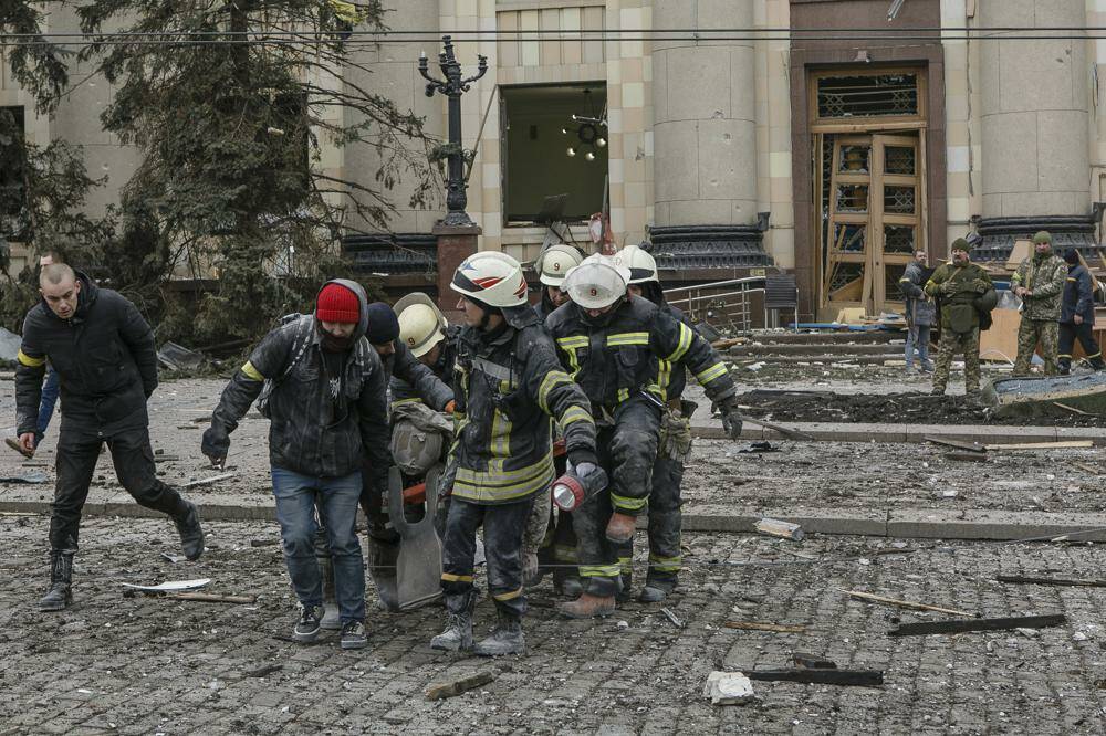 Ukrainian emergency service personnel carry a body of a victim out of the damaged City Hall building following shelling in Kharkiv, Ukraine, Tuesday, March 1, 2022. Russia on Tuesday stepped up shelling of Kharkiv, Ukraine’s second-largest city, pounding civilian targets there. Casualties mounted and reports emerged that more than 70 Ukrainian soldiers were killed after Russian artillery recently hit a military base in Okhtyrka, a city between Kharkiv and Kyiv, the capital. (AP Photo/Pavel Dorogoy)