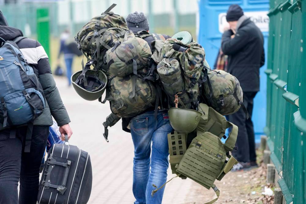 A man carries combat gear as he leaves Poland to fight in Ukraine, at the border crossing in Medyka, Poland, Wednesday, March 2, 2022. (AP Photo/Markus Schreiber)