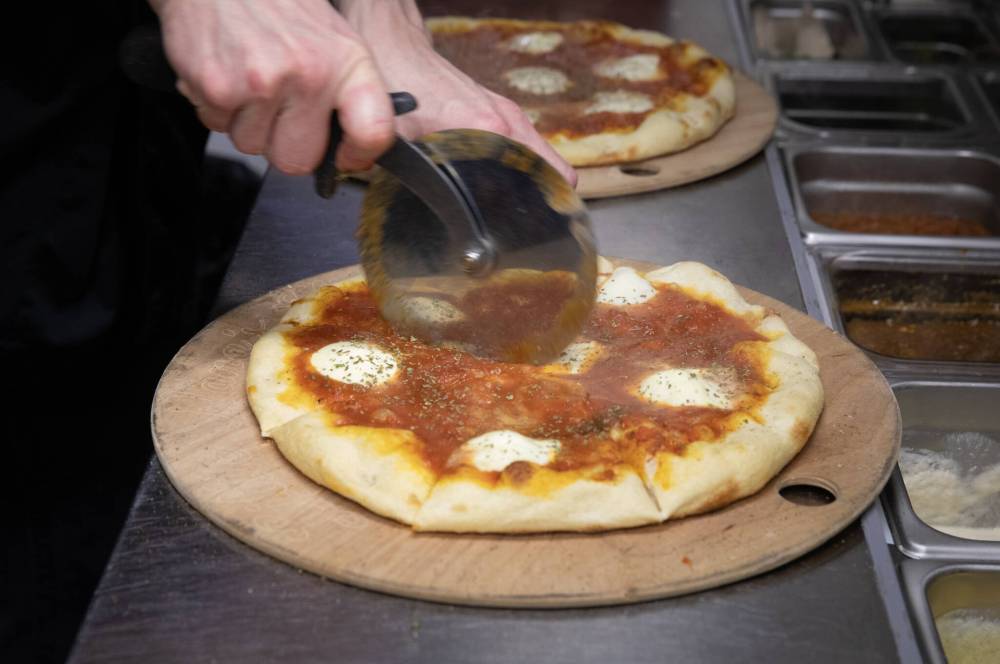 JESSICA LEE / WINNIPEG FREE PRESS
Sous chef Houston Price slices up a Margherita pizza.
